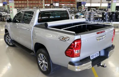 Toyota Hilux prata com capota marítima, estribo lateral e engate traseiro instalada em ambiente automotivo, destacando acessórios para Toyota Hilux que oferecem proteção, estilo e funcionalidade.