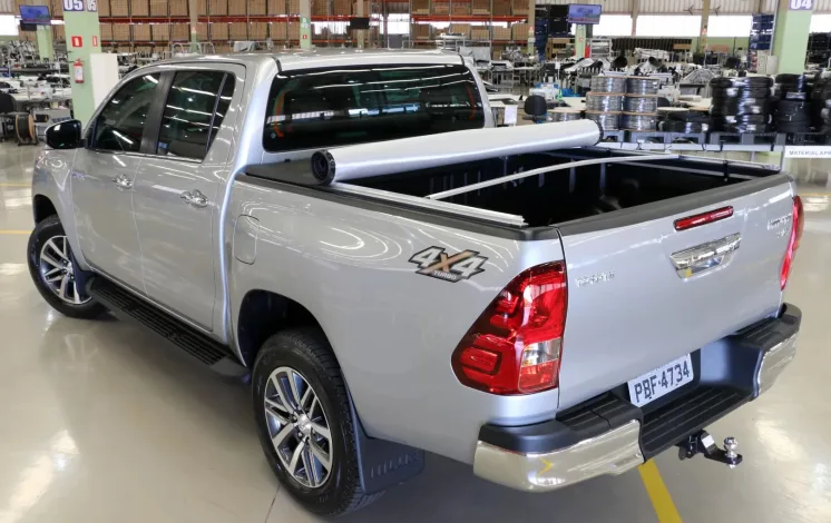 Toyota Hilux prata com capota marítima, estribo lateral e engate traseiro instalada em ambiente automotivo, destacando acessórios para Toyota Hilux que oferecem proteção, estilo e funcionalidade.